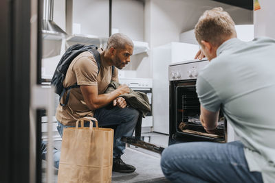 Salesman advising male customer in buying modern appliance at electronics store