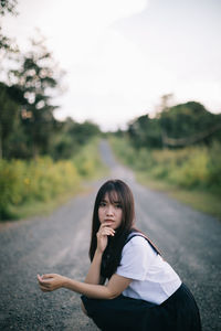 Portrait of woman standing on road against trees