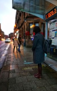 Rear view of woman walking on road in city