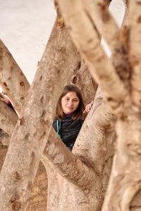 Portrait of girl seen through tree trunk