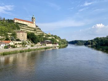 View of castle by river against cloudy sky