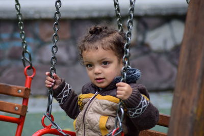 Girl looking away while sitting on swing