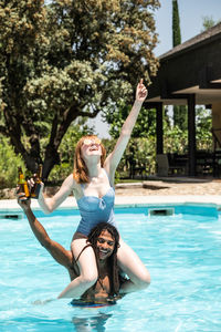 Happy man carrying girlfriend on shoulders in swimming pool