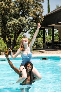 Happy man carrying girlfriend on shoulders in swimming pool