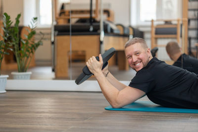 Male fitness pilates trainer shows exercises on special simulators. rubber rings for stretching