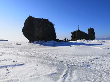 Scenic view of snow covered land against clear blue sky