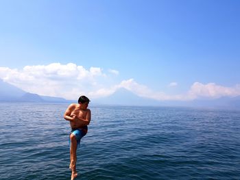 Full length of shirtless man jumping in sea