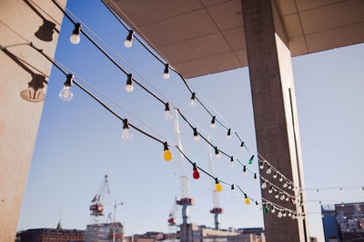 A view of port cranes against clear sky from under christmas decorations