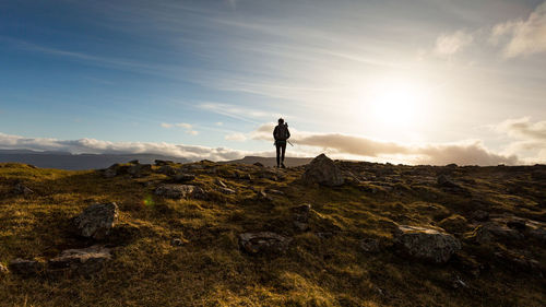 Man standing on mountain against sky during sunset
