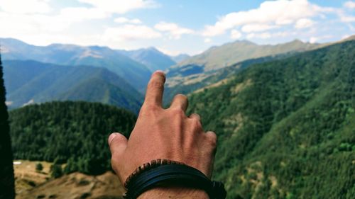 Cropped hand of man against mountain range