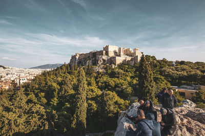 People sitting on mountain against sky