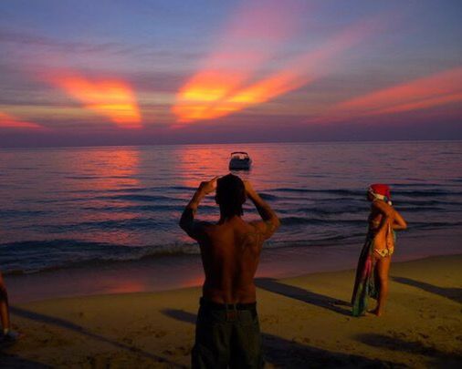 sunset, sea, water, lifestyles, horizon over water, sky, leisure activity, standing, orange color, men, rear view, beach, scenics, beauty in nature, full length, shore, silhouette, tranquil scene