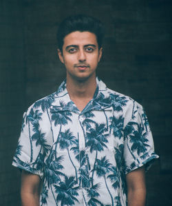 Portrait of young man standing against wall