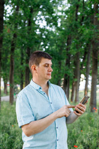 Man using mobile phone while standing by plants