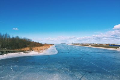Scenic view of frozen landscape against blue sky