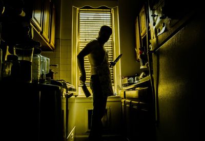 Scary silhouette of a man holding a knife in the kitchen 