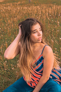 Beautiful young woman sitting on field