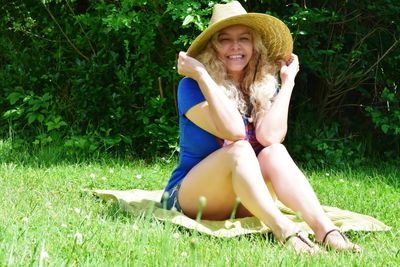 Portrait of smiling young woman sitting on mat at park