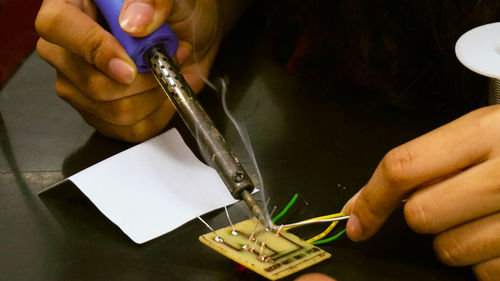 Cropped hands soldering computer chip