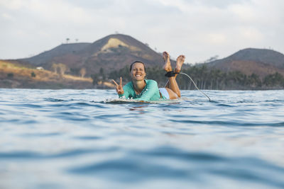 Smiling young woman lying on surfboard