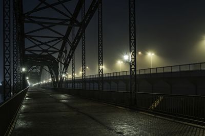 Diminishing perspective of bridge against sky at night