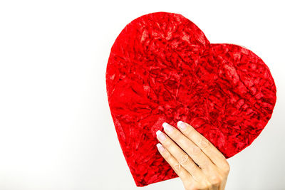 Close-up of hand holding heart shape over white background