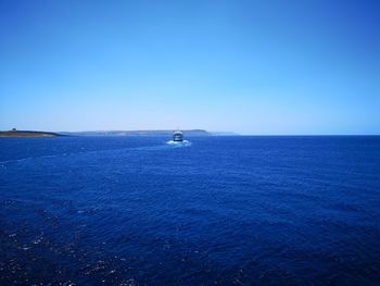 Sailboat in sea against clear blue sky