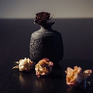 Wilted roses by vase on table