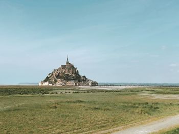 Scenic view of landscape and building by sea against sky