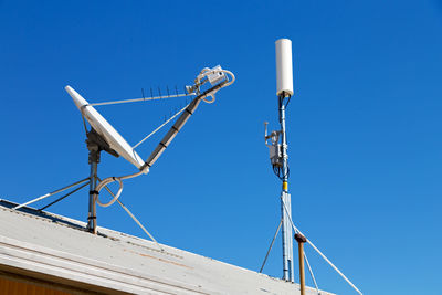 Low angle view of communications tower against clear blue sky