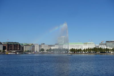Fountain amidst lake against buildings in city