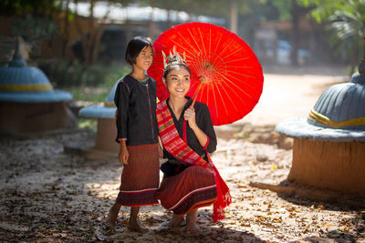 Full length of man holding woman with umbrella