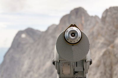 Close-up of coin-operated binoculars on rock against sky