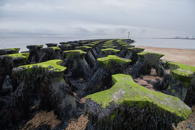 Scenic view of rocks by sea against sky