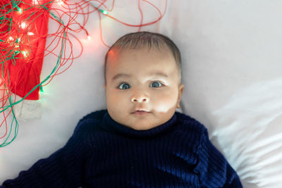 Infant boy lying with colorful lights cute facial expression with white background at indoor
