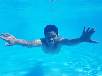Portrait of young man swimming underwater in pool