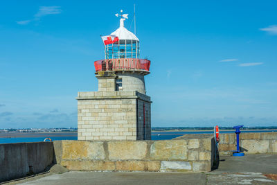 Lighthouse by sea against sky