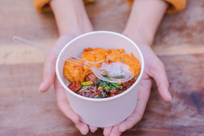 Close-up of hand holding bowl of food