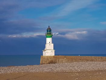 Lighthouse by sea against sky