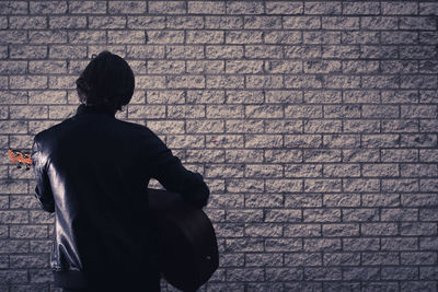 Rear view of man standing against brick wall