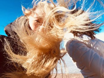 Woman tossing hair by friend at beach