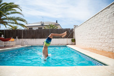 Man jumping in swimming pool against sky