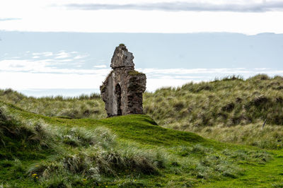 Stone structure on field against sky