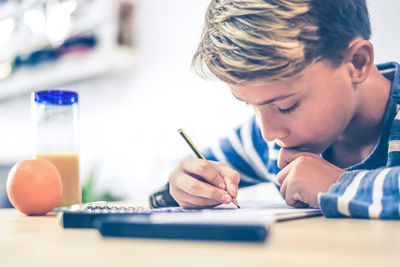 Close up view of student drawing with pencil. boy doing homework writing on a paper. kid hold pencil