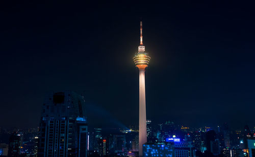 Communications tower in city against sky at night