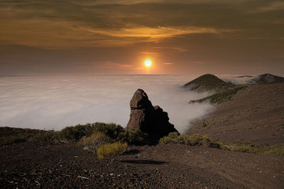 Rock formation on land against sky during sunset