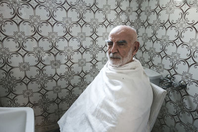Portrait of man wearing eyeglasses against white wall