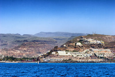 Scenic view of sea and mountains against clear blue sky