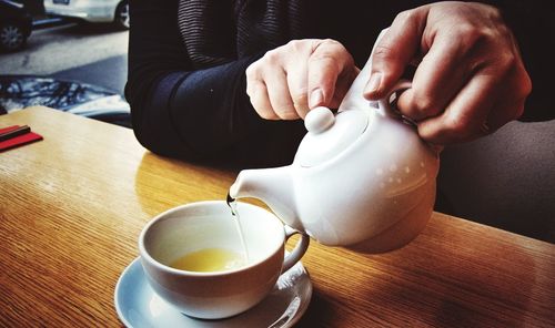 Midsection of man pouring tea in cup on restaurant table