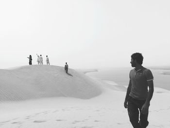 Men at desert against clear sky